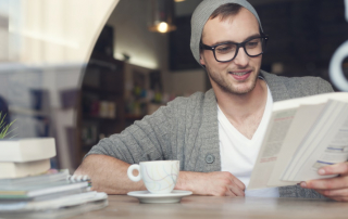 Lächelnder Mann liest Buch im Café