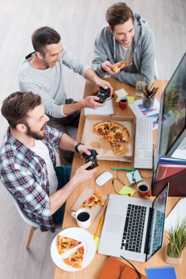 Männer spielen Computer und essen Pizza