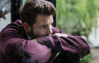 Trauriger Mann schaut bei Regen aus dem Fenster