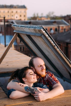 Paar beim Date steht in geöffneter Dachluke und betrachtet die Landschaft