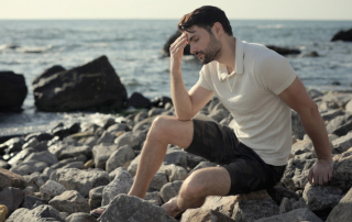 Trauriger Mann sitzt allein am Meer