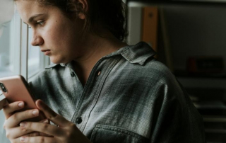 Frau schaut traurig aus dem Fenster, weil Mann sich nicht meldet