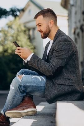 Mann schaut lächelnd auf sein Smartphone