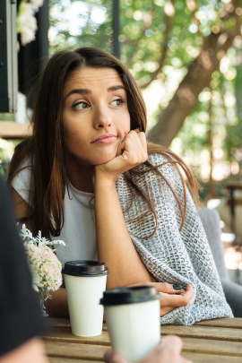 Frau sitzt nachdenklich beim Date im Café